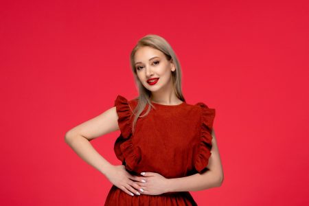 red dress elegant cute young woman wearing burgundy dress with lipstick on red wallpaper