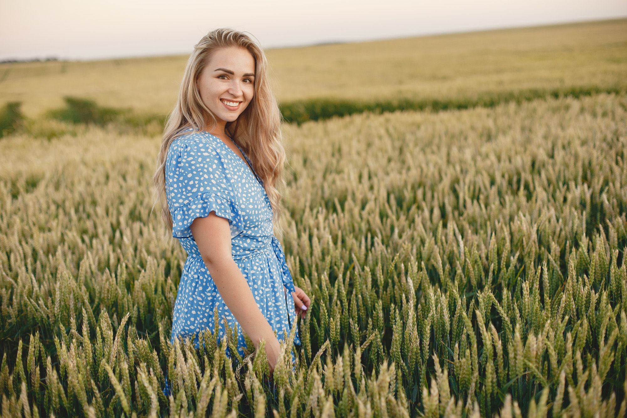 Woman in a blue dress in a wheat field